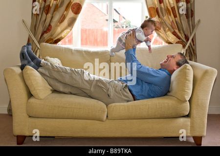 Portrait d'un père horizontale jouer avec son bébé nouveau-né fille allongée sur un canapé Banque D'Images