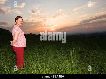 Femme enceinte 28 ans et coucher du soleil à l'extérieur Banque D'Images