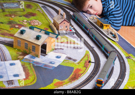 Jeune garçon jouant avec un modèle toy train électrique situé dans ho gauge avec moteurs à partir du modèle de chemin de fer Hornby et Bachmann Banque D'Images