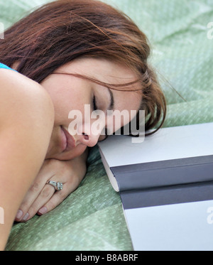 Une jeune femme, 20 ans, pan sur une couverture en plein air après la lecture. Banque D'Images