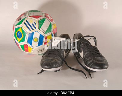 Une vieille paire de chaussures de football soccer utilisé et un ballon de foot Banque D'Images