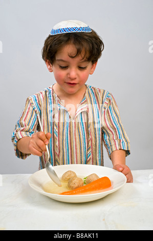 Jwish jeune garçon ayant matzo ball soup Banque D'Images