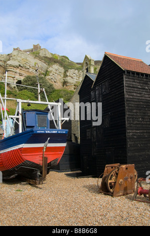 Hastings, East Sussex, Angleterre, Royaume-Uni. Bateau de pêche parmi les boutiques 'net' (abris pour les filets de pêche) suspendus Banque D'Images