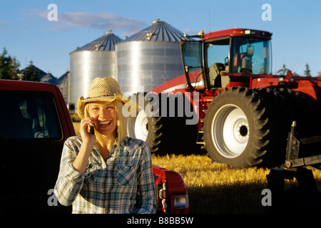 Farm Girl talking Téléphone cellulaire, les cellules à grains du tracteur, l'arrière-plan, Dugald Manitoba Banque D'Images