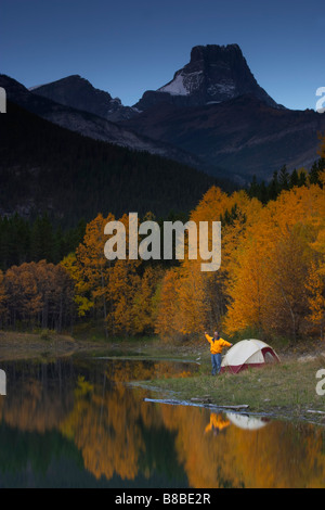 L'homme s'étend à côté de l'étang par tente, montagnes de l'Alberta Kananaskis Banque D'Images