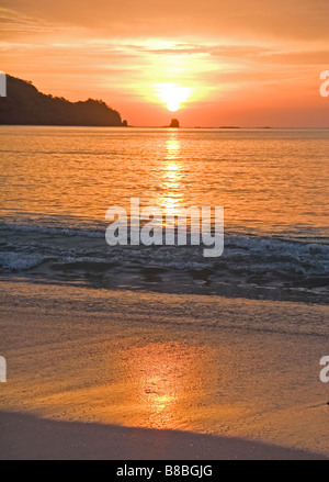 Un beau coucher du soleil orange compte dans le sable humide Banque D'Images