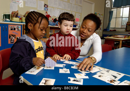 Travailleuse en garderie jouer Jeu de mémoire pour les enfants de quatre ans Banque D'Images