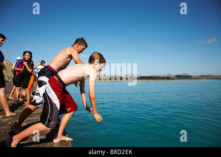 12 enfants de sauter dans la mer du quai Banque D'Images