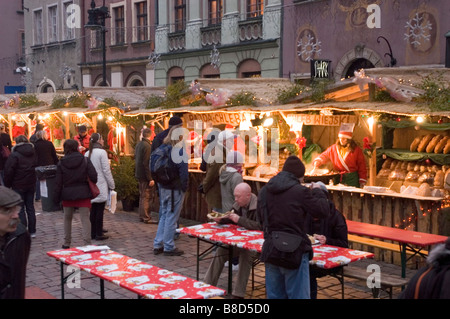 Les stands de nourriture traditionnelle sur la place du Vieux marché, Poznan, Pologne, lors d'un marché de Noël festif avec des gens dînant à des tables en plein air. Banque D'Images