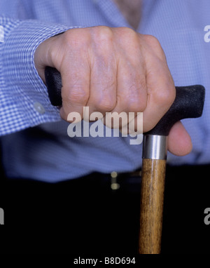 Gros plan d'un homme handicapé âgé seul à la maison saisissant une canne ou un bâton de marche. Main et canne uniquement Banque D'Images