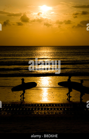 Les surfeurs sur la plage de Kuta, Bali, au coucher du soleil Banque D'Images