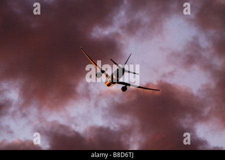 Jet Avion au décollage en nuages au coucher du soleil avec une bordure d'éclairage. Banque D'Images