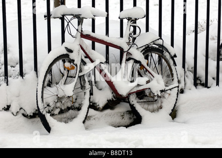 Un vélo couvert de neige attaché à balustrades victoriennes à Brunswick Square Hove East Sussex. Banque D'Images