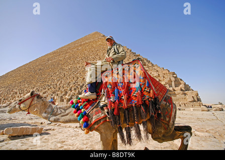 Le Caire, Égypte. Un jeune homme égyptien sur un chameau par la grande pyramide de Khéops à Gizeh. Banque D'Images