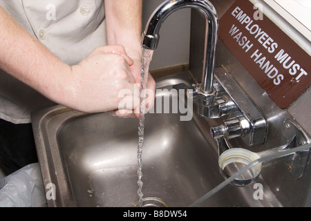 Employé du restaurant, se laver les mains dans le lavabo avec les employés doivent se laver les mains sign Banque D'Images