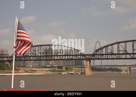 Drapeau américain en face d'un pont routier sur le fleuve du Mississippi avec le gateway arch dans l'arrière-plan Banque D'Images