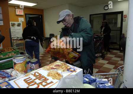 Un des sacs d'épicerie à son client la banque alimentaire de NYC Food Pantry dans le quartier de Harlem, New York Banque D'Images