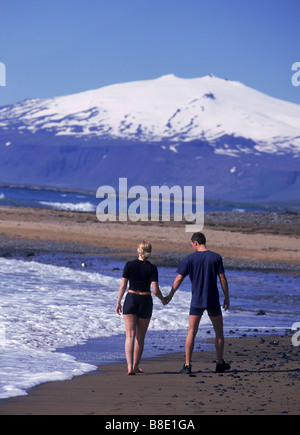 Couple waking sur plage avec en arrière-plan Glacier Snaefellsjokull, Péninsule de Snæfellsnes Banque D'Images