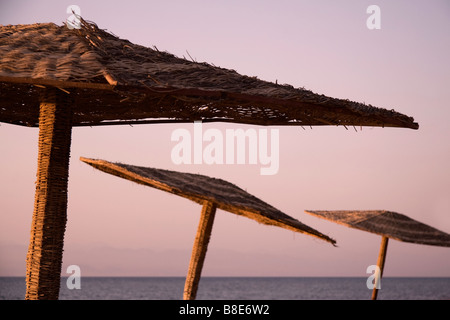 Résumé L'osier des parasols sur une plage égyptienne au lever du soleil avec la Mer Rouge à l'arrière-plan Banque D'Images