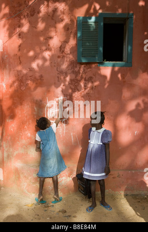 Fille sénégalais écrit sur un mur avec de la craie sur l'Ile de Gorée au Sénégal Afrique de l'Ouest Banque D'Images