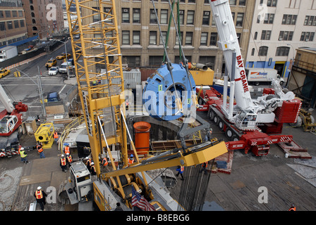 Les travailleurs de la construction se préparer pour abaisser la tête de coupe de 100 tonnes d'un tunnelier en bas d'un arbre dans une chambre d'assemblée Banque D'Images