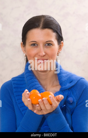 Belle Jeune femme tenant un fruit mandarin Banque D'Images