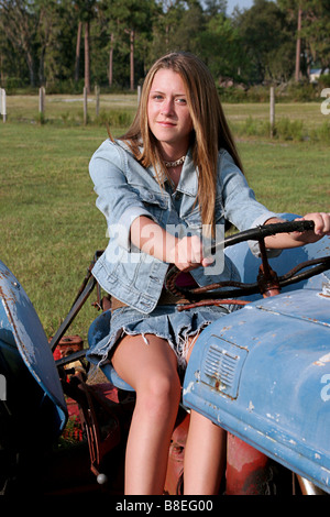 Une belle fille blonde au volant d'un tracteur Banque D'Images