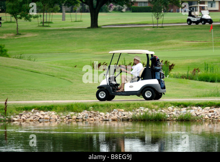 Un homme conduit un chariot de golf a passé les risques liés à l'eau sur Hefner golf à Oklahoma City, Oklahoma, USA. Banque D'Images