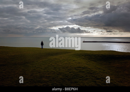 Une jeune femme regarde la mer depuis une colline surplombant le port de Folkestone Banque D'Images