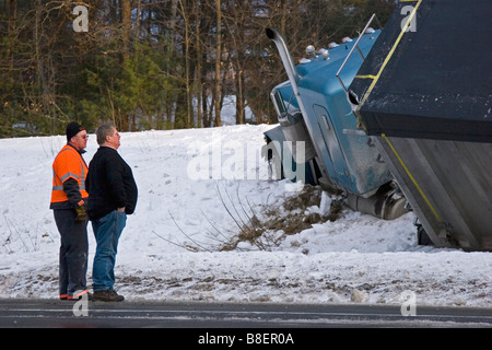 Semi truck dans les fossés dans la neige avec des hommes à la recherche sur Banque D'Images