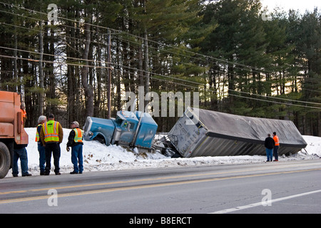 Semi truck dans les fossés dans la neige avec des hommes à la recherche sur Banque D'Images