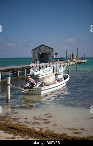 Un petit bateau piggy-backs sur un autre bateau plus grand dans les bas-fonds en face d'une jetée en bois près de SanPedro sur Ambergris Caye Banque D'Images