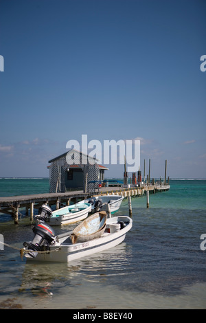 Un petit bateau piggy-backs sur un autre bateau plus grand dans les bas-fonds en face d'une jetée en bois près de SanPedro sur Ambergris Caye Banque D'Images