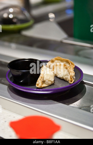 Les contenants des sushis dans un restaurant sur une ligne Banque D'Images