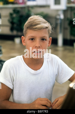 Garçon blond en blanc T shirt regarde attentivement at camera Banque D'Images