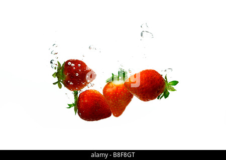 Fraises rouges frais dans l'eau créant des bulles Banque D'Images