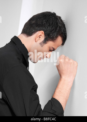 Homme frustré posant sa tête sur un mur Banque D'Images