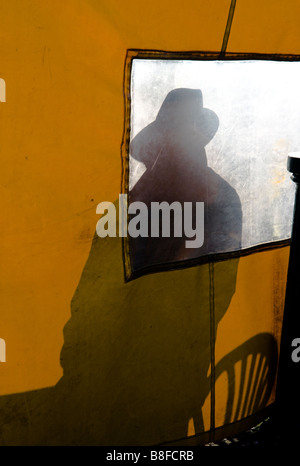Silhouette d'un homme portant un chapeau à large hat vu à travers l'écran jaune Banque D'Images