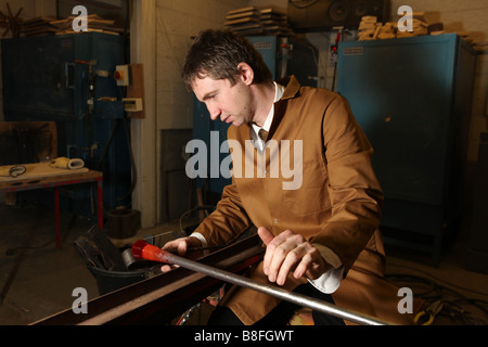 Un souffleur de verre professionnel prend du verre en fusion sur une chaudière prête à exploser et la forme dans un vase ou verre ornement Banque D'Images