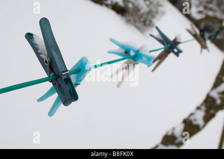 Chevilles de chiffons à gauche sur une ligne de lavage après une chute de neige en vouloir Banque D'Images