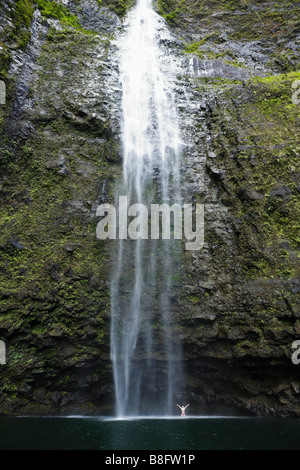 Une femme debout sous Hanakapi ai Falls avec ses bras jusqu'à l'ia Hanakapi vallée sur la côte de Na Pali de Kauai Hawaii Banque D'Images