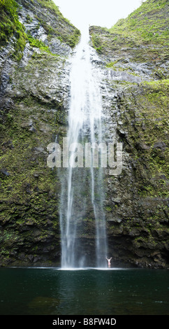 Une femme debout sous Hanakapi ai Falls avec ses bras jusqu'à l'ia Hanakapi vallée sur la côte de Na Pali de Kauai Hawaii Banque D'Images