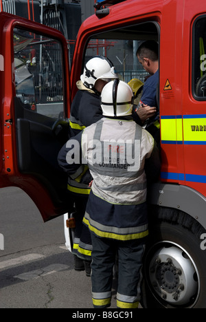 Commandant de l'intervention incendie consulte des collègues tout en passant messages informatifs sur incident à la radio Banque D'Images