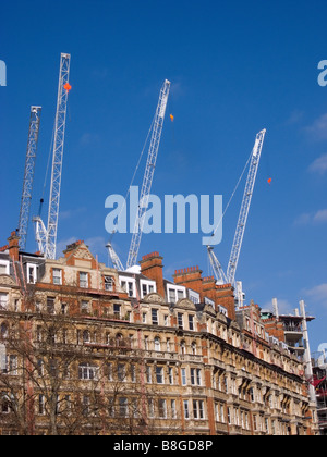 Trois grues à tour de flèche relevable et une grue a tour en cours d'utilisation sur un chantier à Knightsbridge Londres derrière le bâtiment existant Banque D'Images