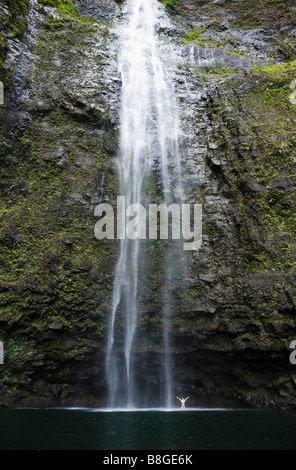 Une femme debout sous Hanakapi ai Falls avec ses bras jusqu'à l'ia Hanakapi vallée sur la côte de Na Pali de Kauai Hawaii Banque D'Images