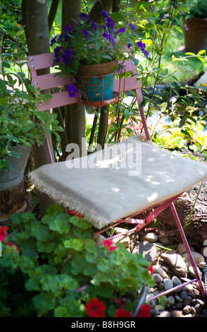 Chaise de jardin en métal rouge avec des pensées dans un pot Banque D'Images