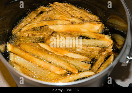 Les frites dans l'huile de cuisson Banque D'Images