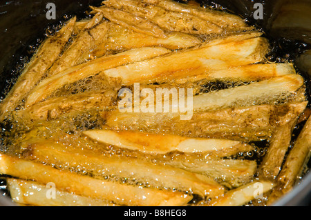 Les frites dans l'huile de cuisson Banque D'Images