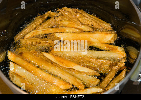 Les frites dans l'huile de cuisson Banque D'Images