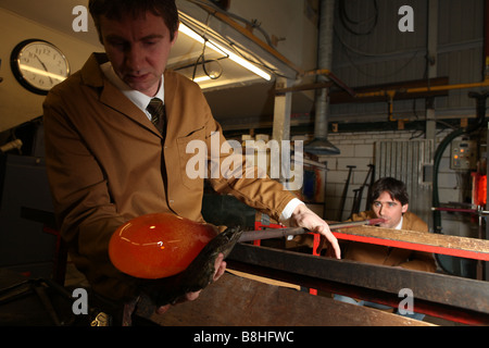 Un souffleur de verre professionnel prend du verre en fusion sur une chaudière prête à exploser et la forme dans un vase ou verre ornement Banque D'Images